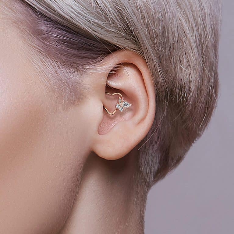 Daith-smycke i hjärtform med kristaller i ett öra